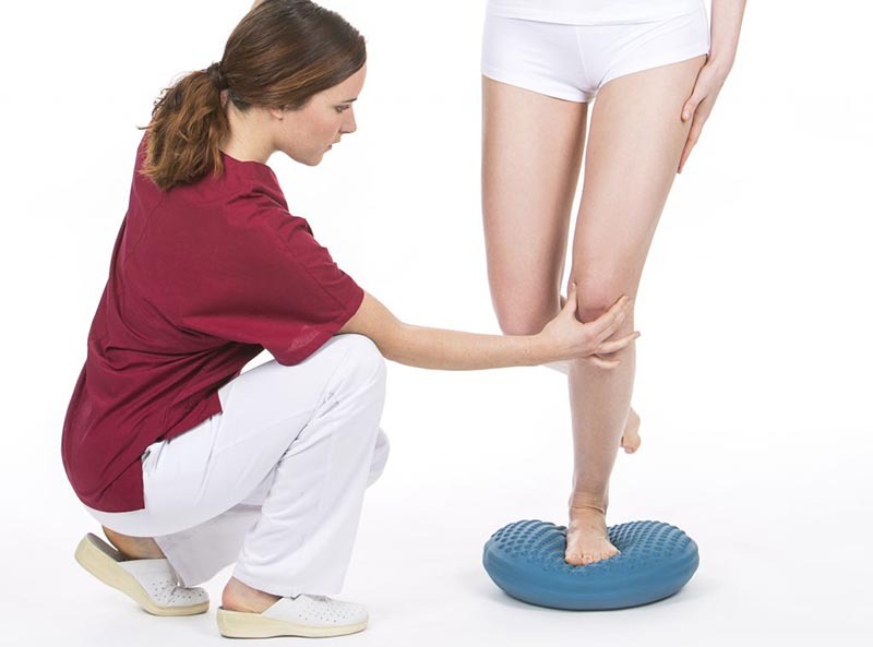Kobieta stojąca na jednej nodze na dysku sensorycznym - ćwiczenia propriocepcji